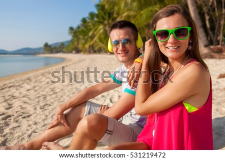 young hipster couple in love, tropical beach, vacation, summer trendy style, sunglasses, headphones