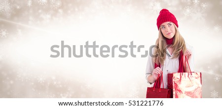 Pretty blonde holding shopping bags against digital composite image of snowflakes