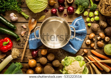 Cooking - empty pot with autumn (fall) vegetables around. Vintage rustic wood as background. Rural kitchen table - flat lay composition (from above, top view). 