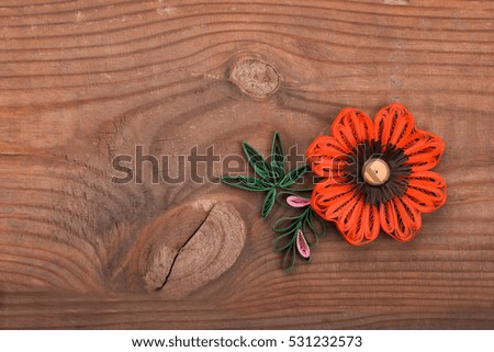 flower made in quilling on a wooden background.