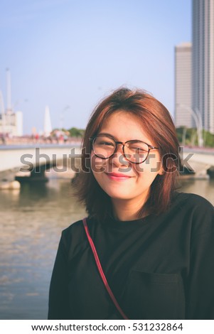 A beautiful Asian woman with glasses smiling with blur background in vintage style.
