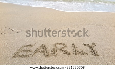 Handwriting words "EARLY" on sand of beach