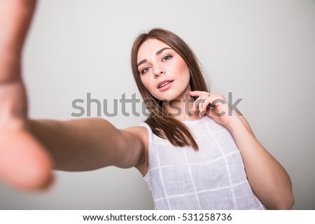 young girl making selfie  on a gray background
