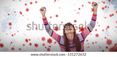 Smiling hipster woman using laptop while putting hands up against snowflake pattern