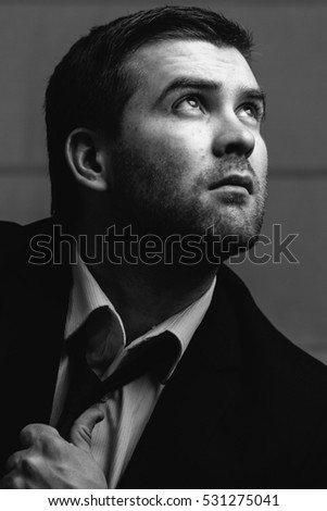Young businessman looks up the light in a dark room. Black and white photography