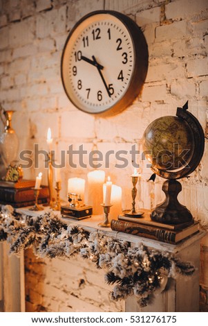 on the mantelpiece stand candle and globe on the wall hung an old clock