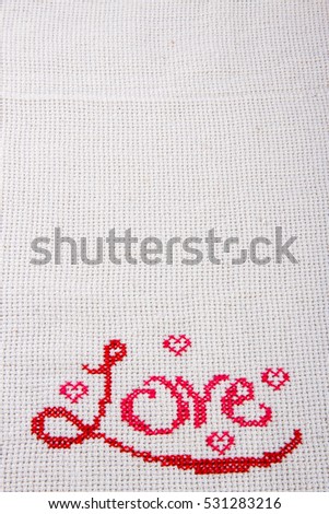 The word "love" embroidered on the canvas by the red thread, the inscription located at the bottom of the photo