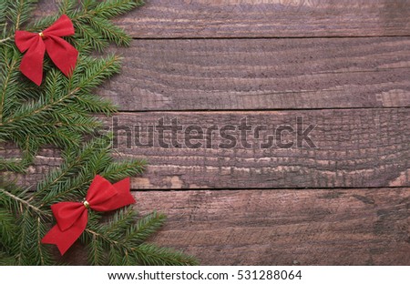 Christmas tree decorated red bow, branches and cones on wooden background.
