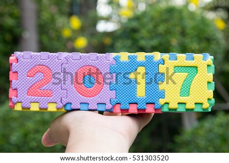 Hand hold Toy alphabet wording 2017 on green background
