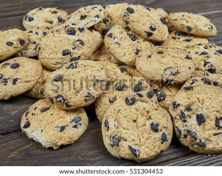 Homemade chocolate chip cookies on dark brown wooden background, showing depth of field