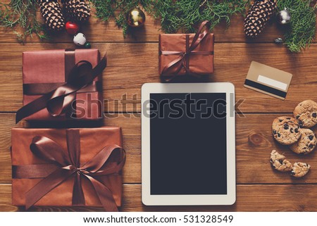 Christmas online shopping background. Tablet screen with copy space top view on wood, credit card and present boxes. Electronic devices, internet commerce on winter holidays concept