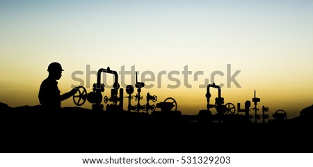Sunset blue hour and silhouette of oilfield worker at oil well manifold   Royalty-Free Stock Photo #531329203