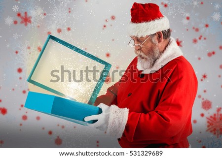 Santa Claus opening gift box against snowflake pattern