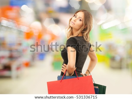 sale and people - woman with colorful shopping bags over supermarket background