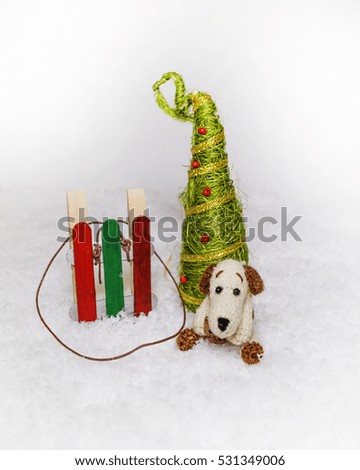 Funny cute knitted dog on the snow background and Christmas tree with sleigh. Christmas greetings card. Children's background.