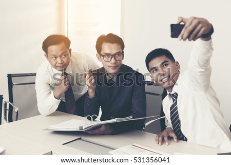 Young people making group photo with smart phone in office.
Group of young businessmen are shooting themselves.