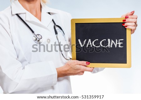 Vaccine Written On Chalkboard Sign Held By Female Doctor.