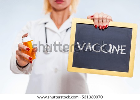 Vaccine Written On Chalkboard Sign Held By Female Doctor Holding Prescription Bottle.