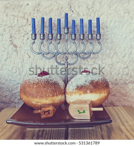 Jewish menorah with candles, sweet donuts and dreidels are traditional symbols for Hanukkah holiday. Image toned for retro style