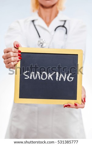 Smoking Written On Chalkboard Sign Held By Female Doctor. Vertical Orientation.