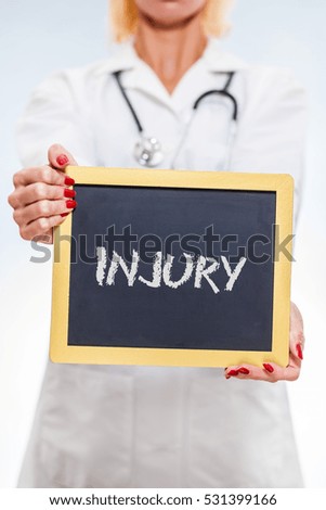 Injury Chalkboard Sign Held By Female Doctor. Vertical Orientation.