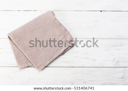 Gray napkin isolated on white wooden table. Copy space. Brick wall background. Front view.