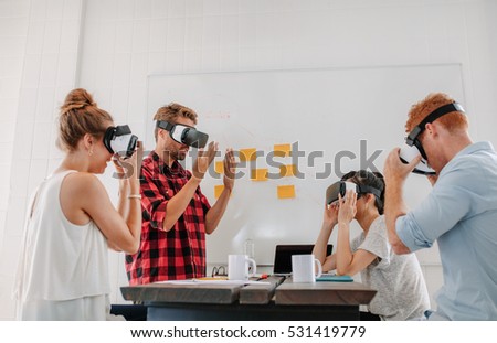 Business people using virtual reality goggles in meeting in office. Team of developers testing virtual reality headset.