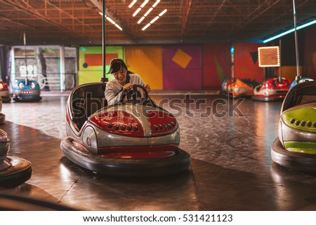 Happy young woman driving a bumper car at amusement park Royalty-Free Stock Photo #531421123