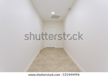White hallway with doors in a fresh painted building.