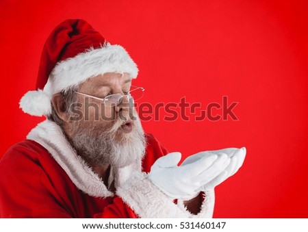 Santa claus pretending to blow imaginary snow against red background