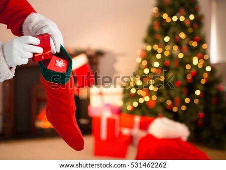 Close-up of Santa Claus putting gift boxes in Christmas stocking