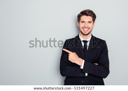Young handsome businessman with beaming smile pointing with finger Royalty-Free Stock Photo #531497227