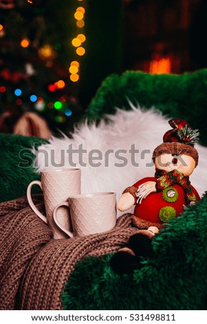 The chair with toy and cups stand near Christmas Tree