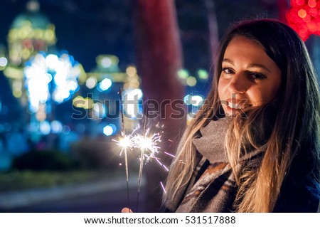 Close up of woman holding sparkler on the street. Girl with sparkler