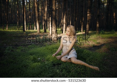 The white-haired girl walks in the woods without shoes, the sun is green grass forest