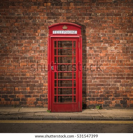Grungy Traditional Red British Telephone Box Against A Red Brick Wall