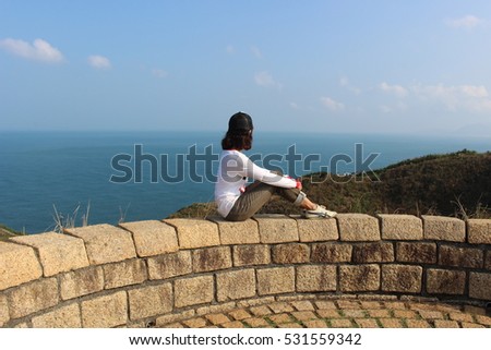 Introverted girl sat on the wall and looked at sea view in Taiwan