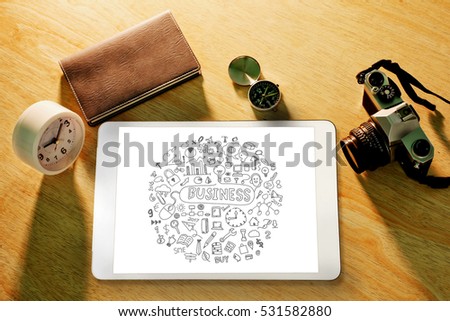 Digital tablet on wood table with business doodle sketches