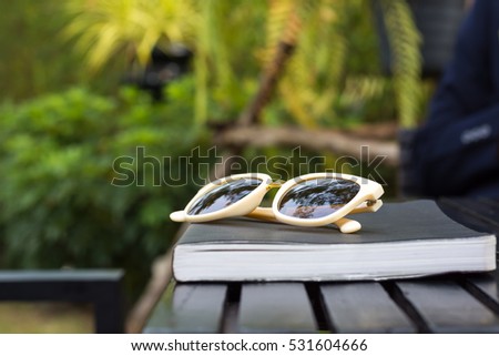 Books with glasses on a wooden table in the garden.