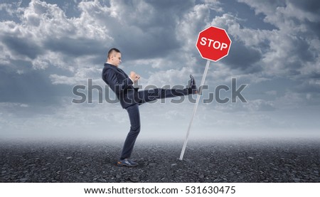 Businessman in a suit standing on the asphalt road and kicking the stop road sing. Business development. Moving forward. Aggressive marketing strategies.