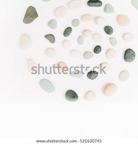 Creative spiral arrangement of colored stones. Mint, pink, beige and grey stones on white. Flat lay, top view