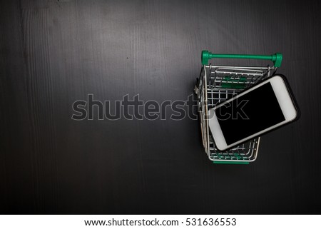 Tablet or smartphone and shopping cart on wood table, Online shopping concept, Top view