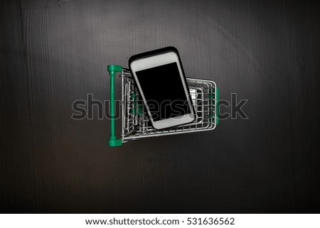 Tablet or smartphone and shopping cart on wood table, Online shopping concept, Top view