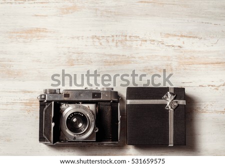 Vintage photo camera on wooden background with gift box. top view. copy space