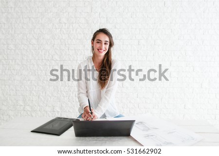 Beautiful designer working with devices, free space. Confident retoucher smiling at camera while sitting at workplace with laptop and graphic tablet. Art, business, creativity concept