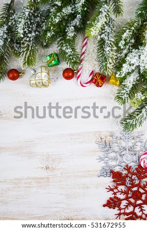 Christmas decorations, gifts and fir branches in the snow on a wooden table. Christmas border closeup.