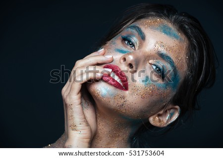 Beauty portrait of gorgeous young woman with blue shining makeup over black background