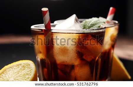 Softdrink with ice cubes, lemon and straw in glass 