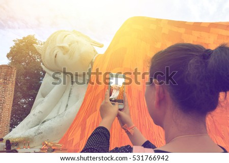 closeup of woman's hands holding mobile phone and taking photo of buddha in Thailand