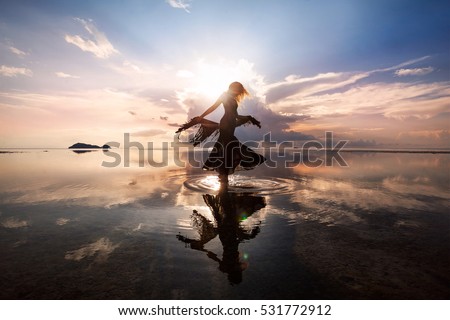 Elegant woman dancing on water. Sunset and silhouette. Royalty-Free Stock Photo #531772912